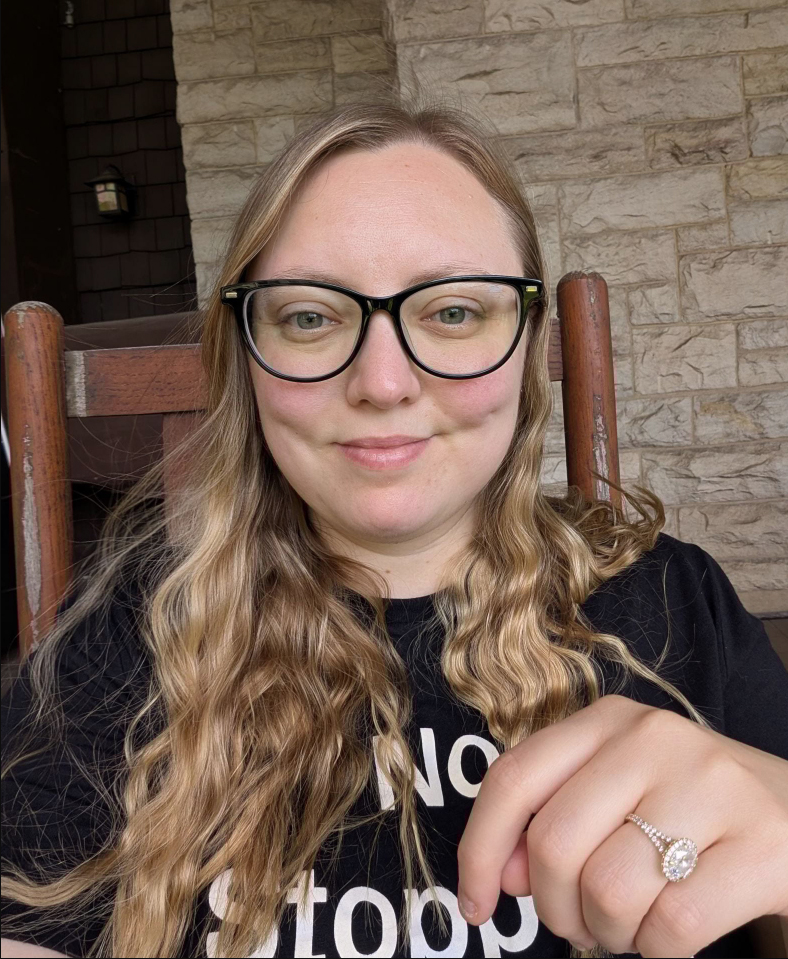 Woman with long blond hair with glasses and black shirt